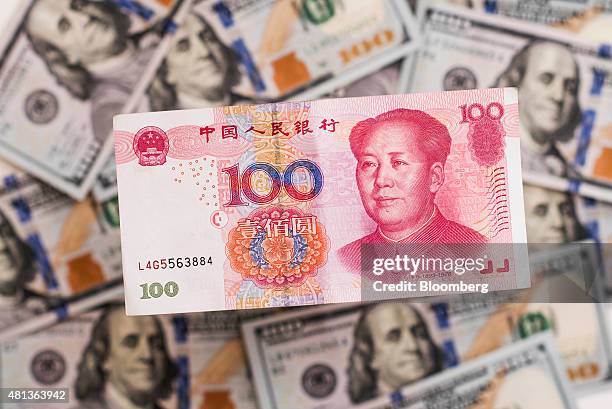 Chinese one-hundred yuan banknote sits on a pile of U.S. One-hundred dollar bills in this arranged photograph taken in Hong Kong, China, on Monday,...