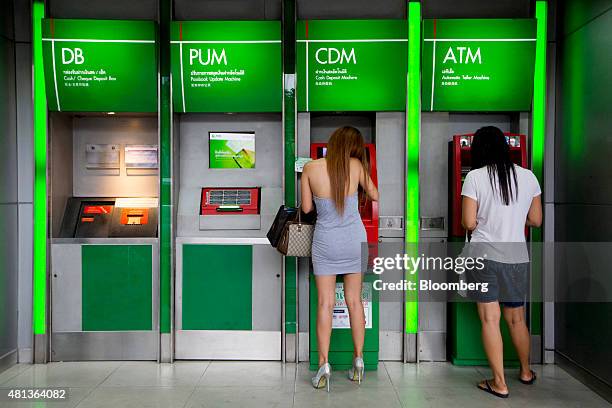 Customers use a cash deposit machine, left, and an automated teller machine outside a Kasikornbank Pcl branch in the Sukhumvit area of Bangkok,...