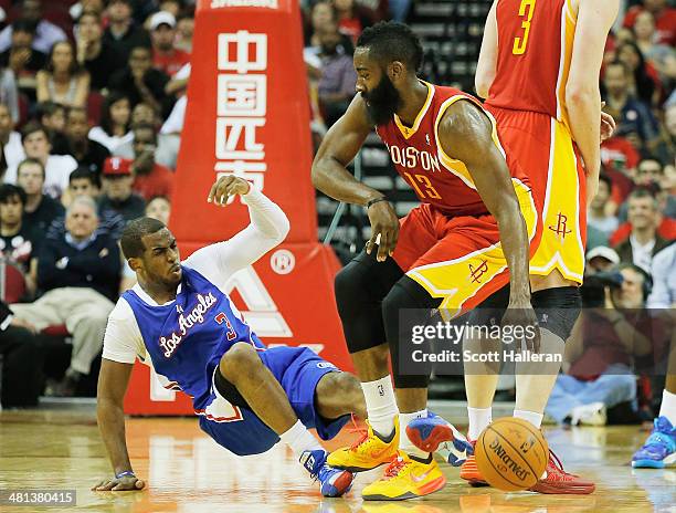 Chris Paul of the Los Angeles Clippers is knocked to the court by James Harden of the Houston Rockets during the game at the Toyota Center on March...