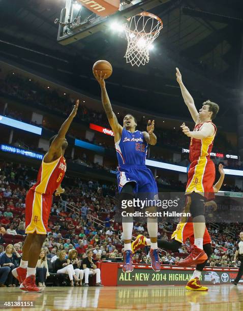 Matt Barnes of the Los Angeles Clippers shoots over Terrence Jones and Omer Asik of the Houston Rockets during the game at the Toyota Center on March...