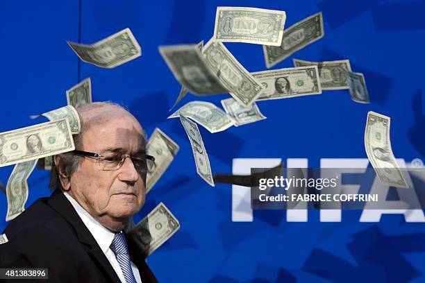 President Sepp Blatter looks on with fake dollars note flying around him thrown by a protester during a press conference at the football's world body...
