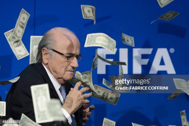 President Sepp Blatter looks on with fake dollars note flying around him thrown by a protester during a press conference at the football's world body...