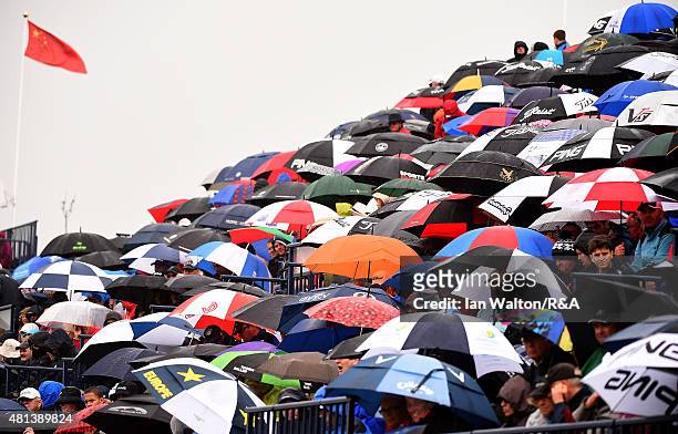 Spectators shelter under their umbrellas as the rain begins to fall during the final round of the 144th Open Championship at The Old Course on July...