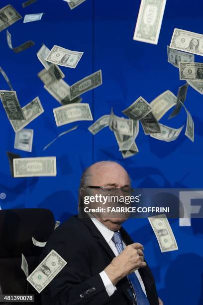 President Sepp Blatter looks on with fake dollars note flying around him thrown by a protester during a press conference at the football's world body...