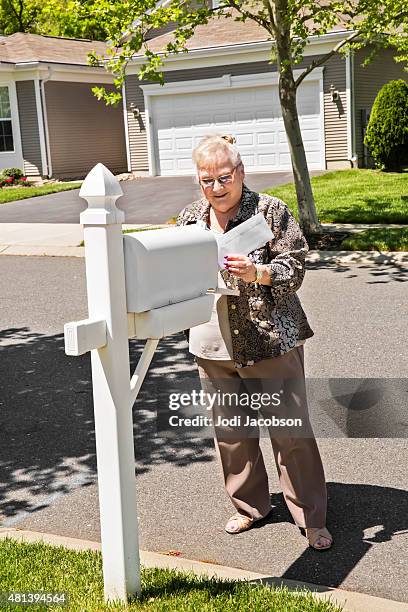 senior caucasian woman getting mail from her mailbox - elderly receiving paperwork stock pictures, royalty-free photos & images