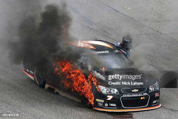 Alex Bowman, driver of the Tommy Baldwin Racing Chevrolet, climbs from his car as it catches fire during the NASCAR Sprint Cup Series 5-Hour ENERGY...