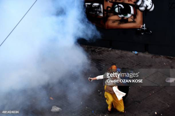 Man and a woman run away from tear gas during a demonstration on July 20,2015 in Istanbul following an explosion in Turkey's southern town of Suruc....