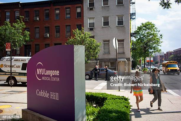 Pedestrians walk on the sidewalk along the Long Island College Hospital campus June 19, 2015 in the Brooklyn borough of New York. The Fortis Property...