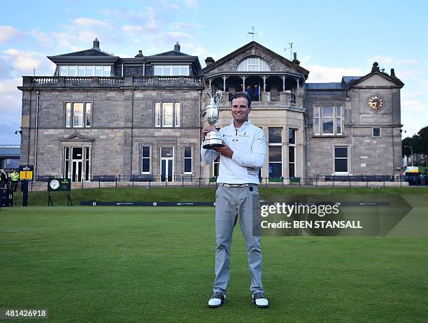 Golfer Zach Johnson holds the Claret Jug, the trophy for the Champion golfer of the year in front of the clubhouse as his poses for a photograph...
