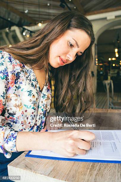 bella empresaria firmar contrato en un café en el interior del hotel - llenar el formulario fotografías e imágenes de stock