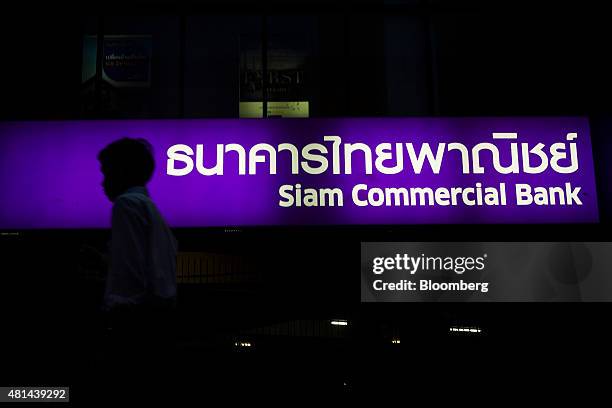 Pedestrian walks past a Siam Commercial Bank branch at night in the Sukhumvit area of Bangkok, Thailand, on Monday, July 20, 2015. Siam Commercial...