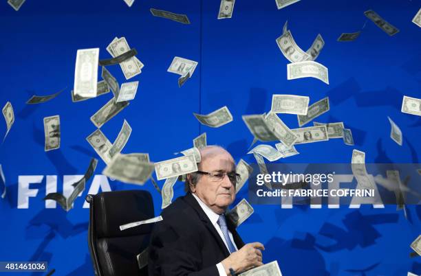 President Sepp Blatter looks on as fake dollar notes fly around him, thrown by a British comedian during a press conference at the FIFA world-body...