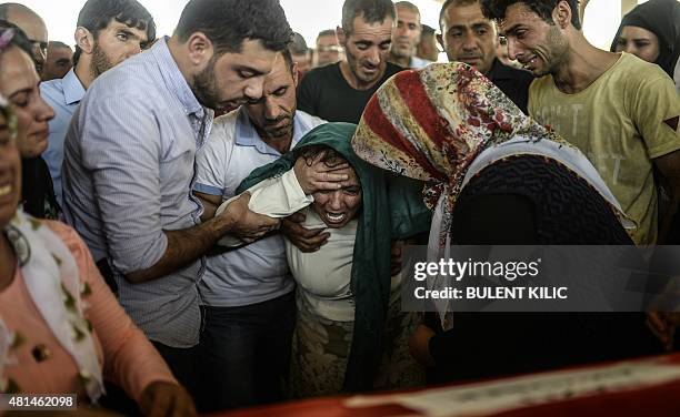 The mother of a victim cries for her son near his coffin during a funeral ceremony in Gaziantep on July 21 following a suicide bomb attack the day...