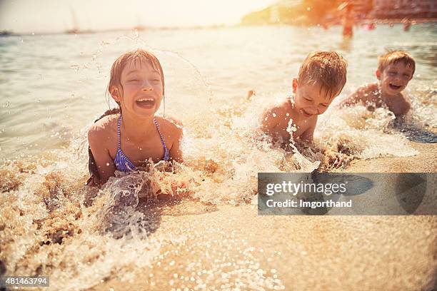 Kids having fun in sea lying on beach