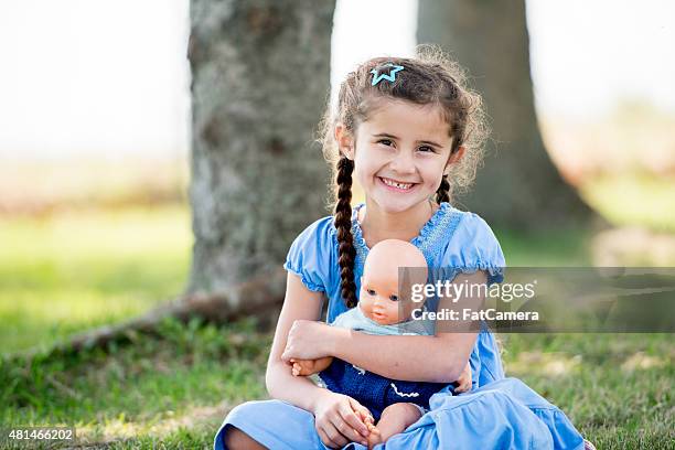 little girl playing with doll at park - baby doll dress stock pictures, royalty-free photos & images