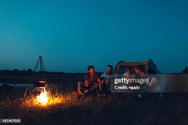 friends camping together. - camping campfire stock pictures, royalty-free photos & images