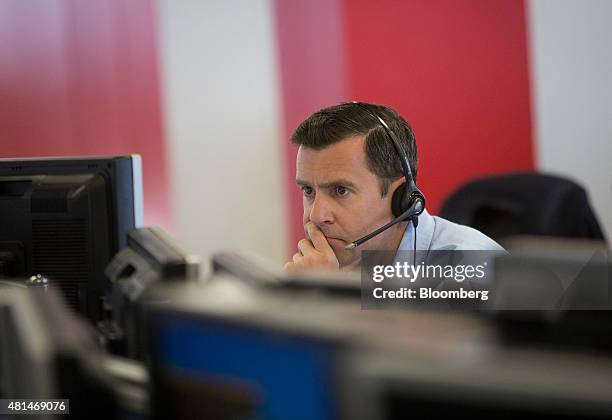 Dealer looks at financial data on computer screens on the trading floor of IG Group Holdings Plc in London, U.K., on Tuesday, July 2015. IG Group...