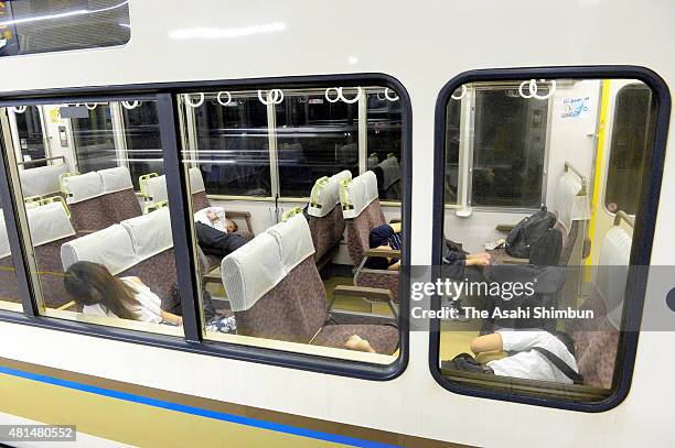 Passengers rest in a train as the service is suspended at Kobe Station as the Typhoon Nangka hits Western Japan on July 18, 2015 in Kobe, Hyogo,...