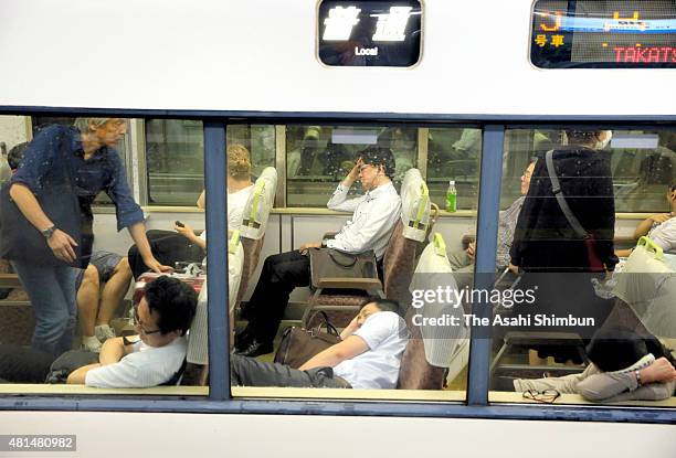 Passengers rest in a train as the service is suspended at Takatsuki Station as the Typhoon Nangka hits Western Japan on July 18, 2015 in Takatsuki,...