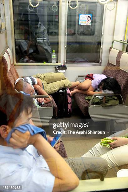 Passengers rest in a train as the service is suspended at Takatsuki Station as the Typhoon Nangka hits Western Japan on July 18, 2015 in Takatsuki,...