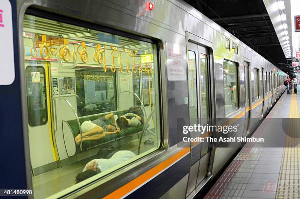 Passengers rest in a train as the service is suspended at Osaka Station as the Typhoon Nangka hits Western Japan on July 18, 2015 in Osaka, Japan....
