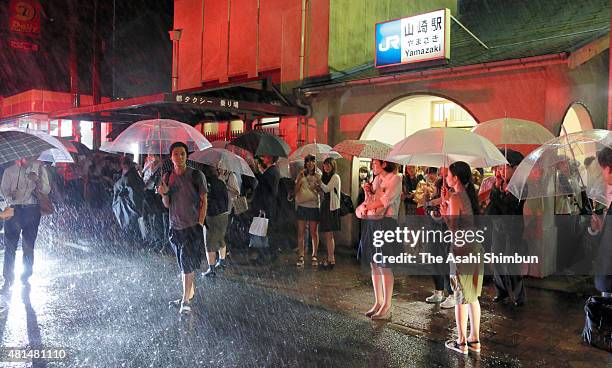 People wait for taxi as the train service is suspended at Yamazaki Station as the Typhoon Nangka hits Western Japan on July 18, 2015 in Oyamazaki,...