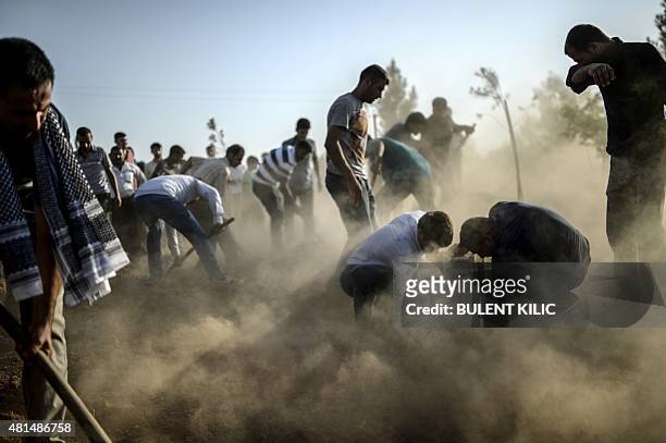 Mourners cover the graves of victims of a suicide bomb attack during their funeral in Suruc in Turkey's Sanliurfa province on July 21, 2015. Turkey...