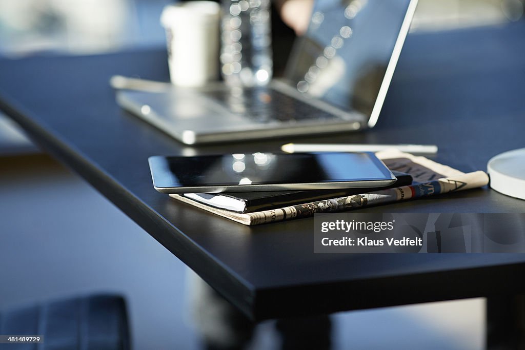 Tablet on top of notebook and newspaper