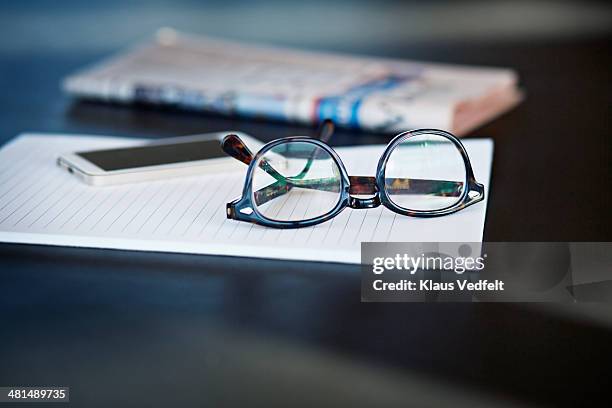 close-up of glasses, phone and paper in back - newspaper on table stock pictures, royalty-free photos & images