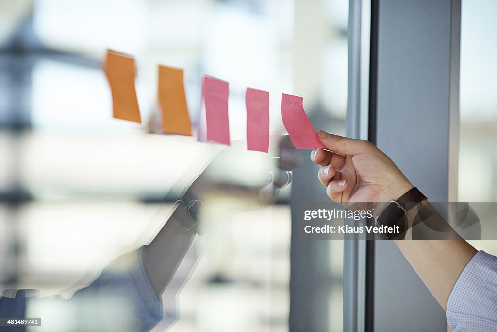 Hand putting Post-It notes on the window