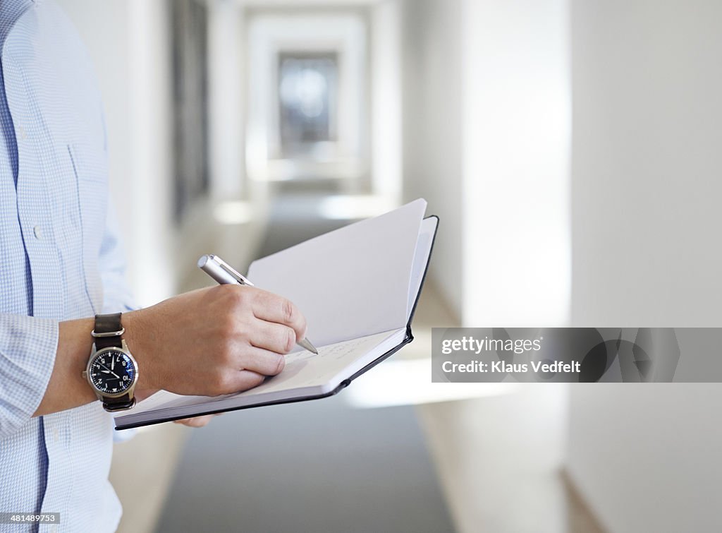 Businessman taking notes in notebook with a pen