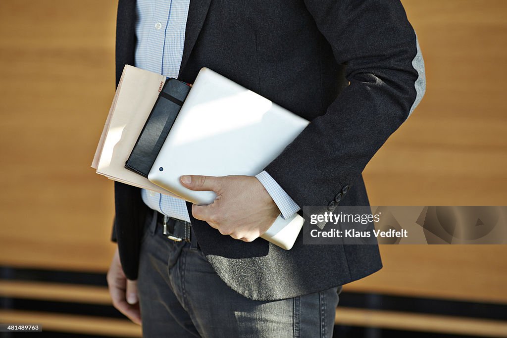 Businessman holding tablet, notebook & newspaper