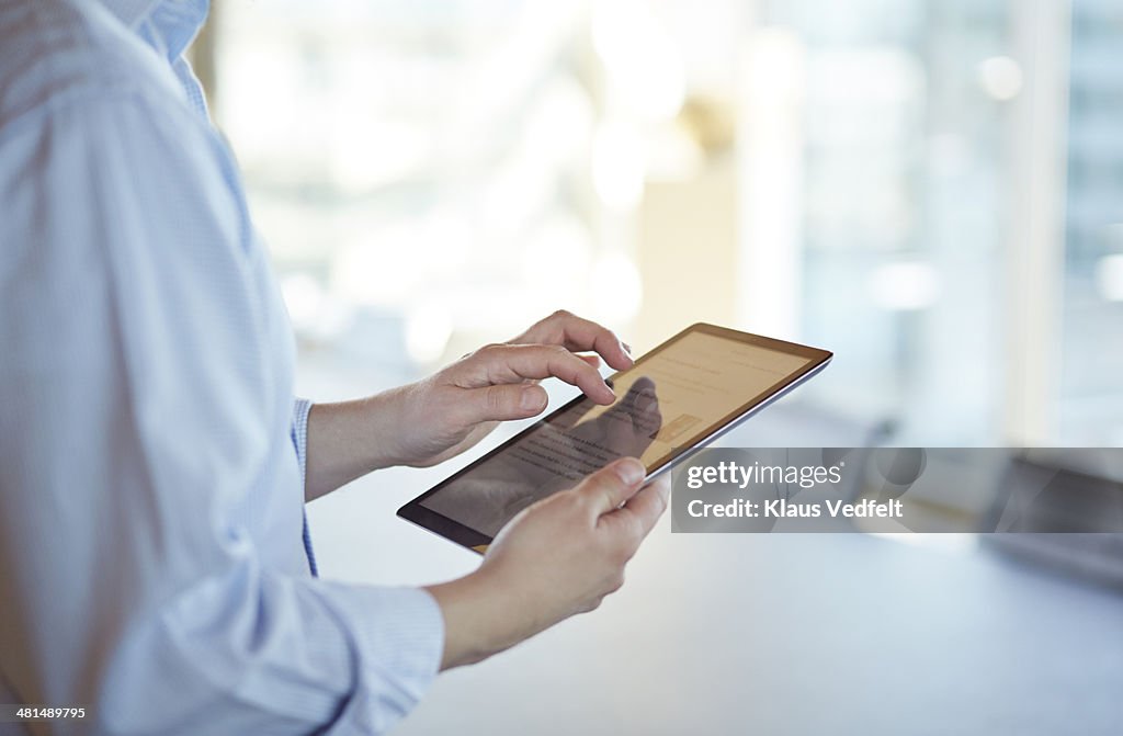 Hands scrolling on tablet, unsharp background