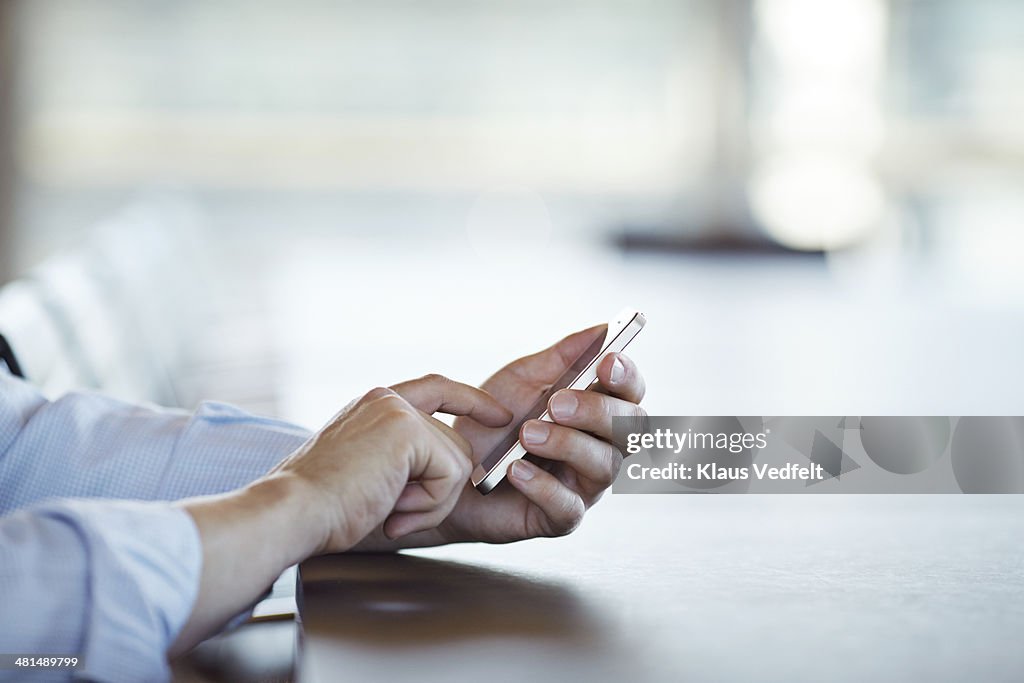 Close-up of hands scrolling on phone, side view.