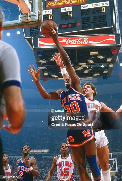 Bernard King of the New York Knicks lays the ball up in front of Kelly Tripucka of the Detroit Pistons during an NBA basketball game circa 1982 at...