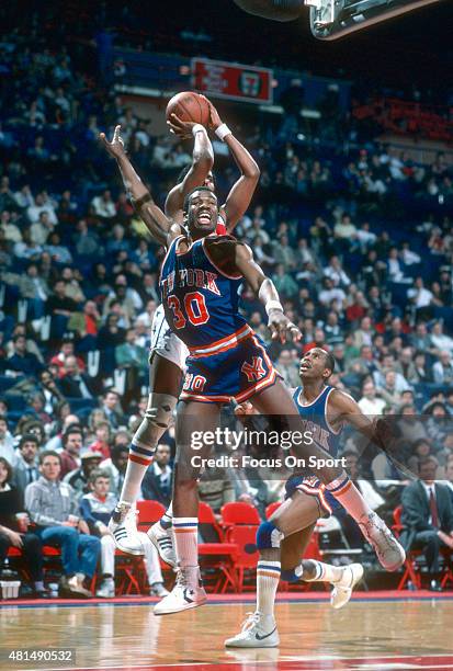 Bernard King of the New York Knicks jumps at shooter Cliff Robinson of the Washington Bullets during an NBA basketball game circa 1985 at the Capital...