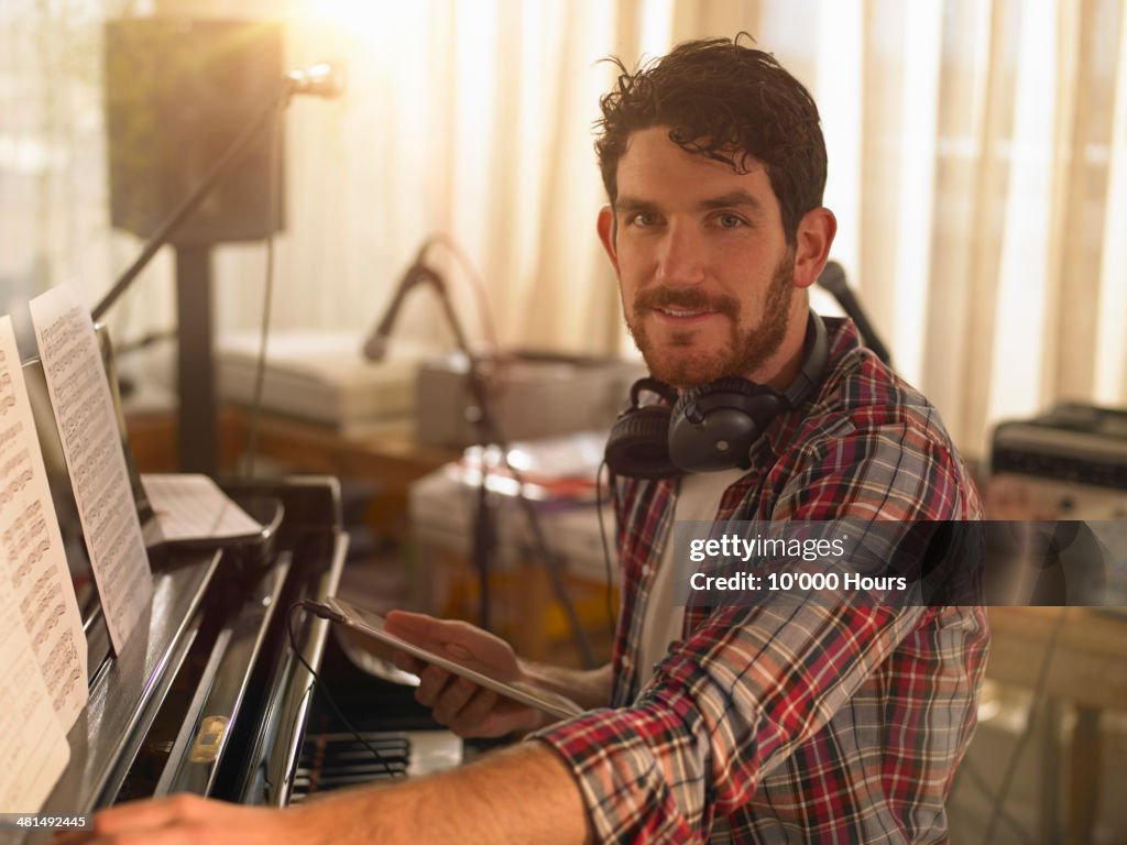 Portrait of a man at a piano holding an tablet computer