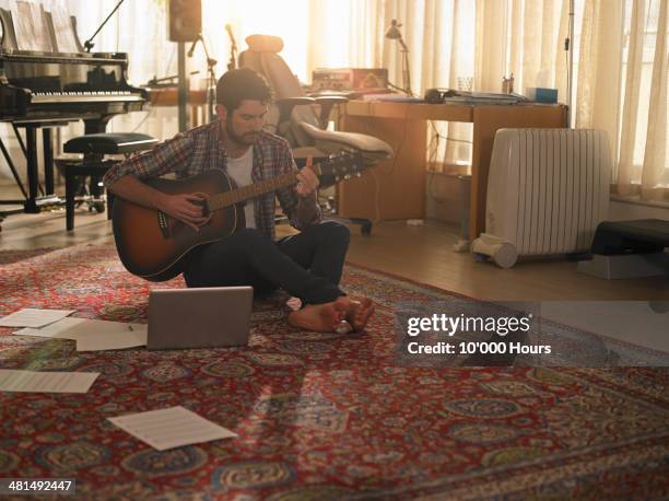 a man playing guitar next to a laptop - saiteninstrument spielen stock-fotos und bilder