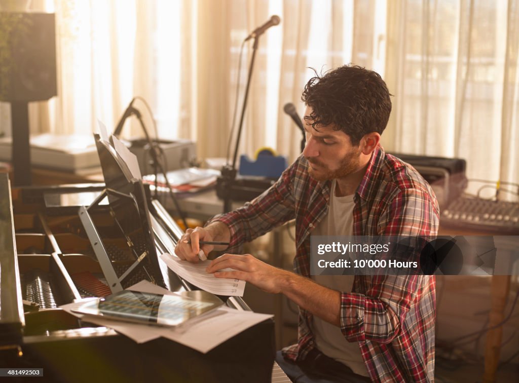 Man writing music on piano and a tablet computer