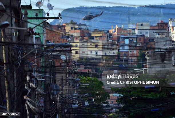 Paramilitary police helicopter overflies the Favela da Mare shantytown complex in Rio de Janeiro, Brazil, on March 30, 2014 early morning. More than...