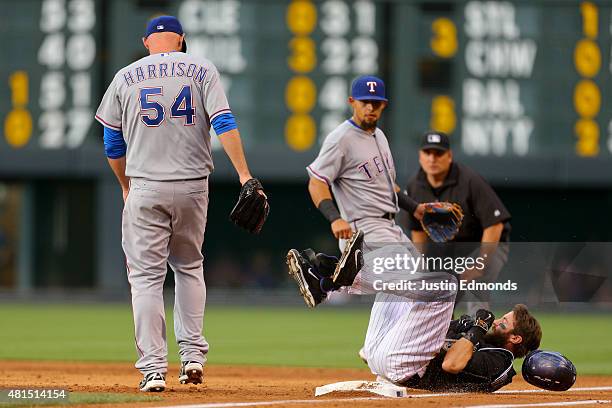Charlie Blackmon of the Colorado Rockies tumbles on the ground after making it safely to first base for an infield single as Matt Harrison of the...