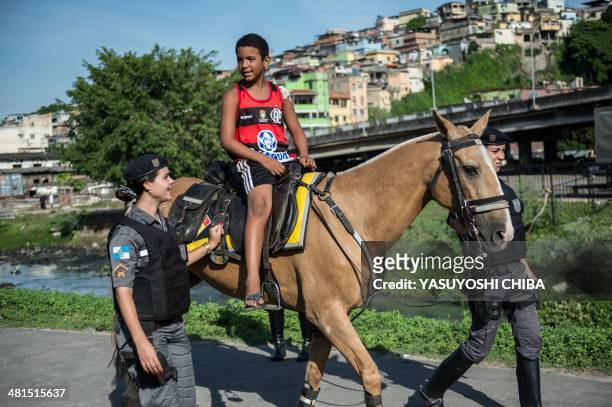 Paramilitary police Batalhao de Choque personnel unit offer a horse ride to a child at the end of the occupation of the Favela da Mare shantytown...