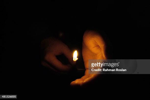Person holds a candle during a candle light vigil to remember the victim of the ill-fated flight MH370 on March 30, 2014 in Kuala Lumpur, Malaysia....