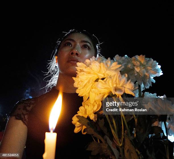 Public member hold a candle during a candle light vigil to remember the victim of the ill-fated flight MH370 on March 30, 2014 in Kuala Lumpur,...
