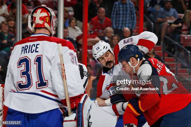 Goaltender Carey Price looks on as George Parros of the Montreal Canadiens squares off against Krys Barch of the Florida Panthers at the BB&T Center...