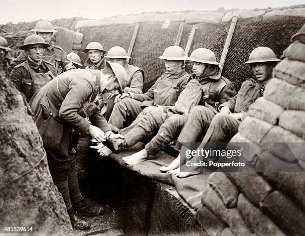 Medical officers attending to the feet of French soldiers in the trenches on the front line during World War One, circa 1915.