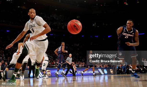 Adreian Payne of the Michigan State Spartans and Phillip Nolan of the Connecticut Huskies chase after a loose ball during the East Regional Final of...