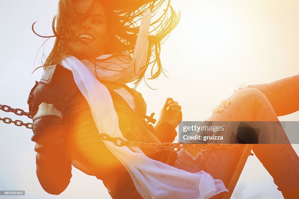 Young woman having fun swinging in sunlight