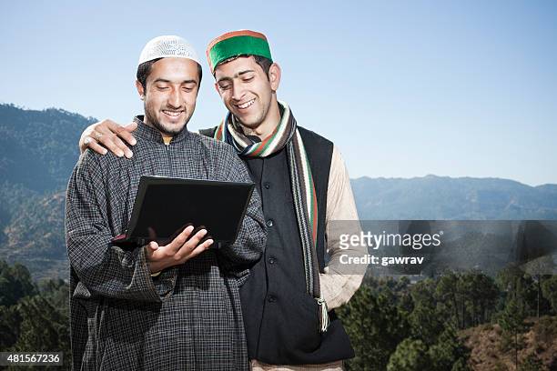 tow happy friends from different cultures of india using laptop. - hindu muslim unity stockfoto's en -beelden
