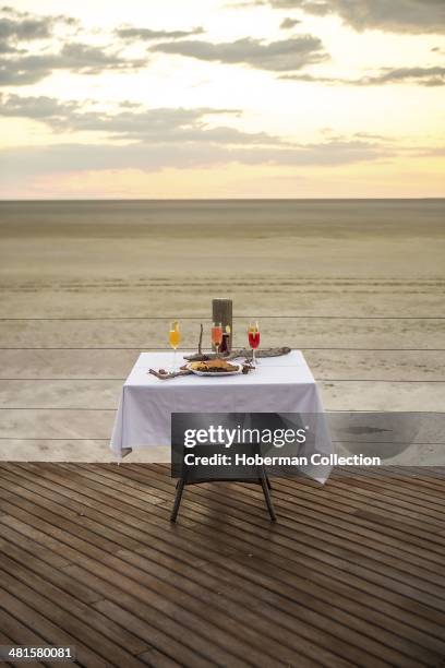 Romantic Dinner Table Set For Two During Sunset On Wooden Decks at Onkoshi Camp On The Eastern Edge Of The Etosha Pan With Vast Landscape Views In...